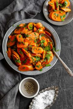 two bowls filled with carrots and herbs