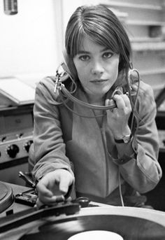 a woman is sitting at a record player and listening to her headphones while holding a turntable