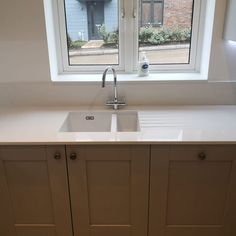 a white kitchen sink sitting under a window