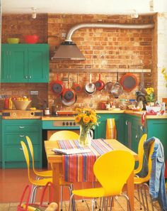 a kitchen with green cabinets, yellow chairs and a wooden table in the foreground