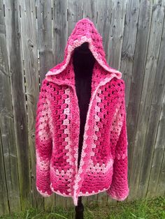 A cropped hooded hexagon cardigan in various shades of pink, offering an oversized and cozy fit suitable for up to an extra-large size. This piece can be safely machine washed on a gentle cycle and dried on low heat. Pink Hexagon Cardigan, Handmade Pink Winter Outerwear, Pink Bohemian Crochet Outerwear, Handmade Pink Cardigan For Fall, Pink Crochet Outerwear For Winter, Bohemian Hand Knitted Pink Cardigan, Handmade Pink Outerwear For Spring, Handmade Pink Bohemian Cardigan, Cozy Handmade Pink Cardigan