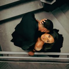 a man and woman standing next to each other on top of a stair case in an office building