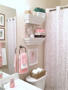 a white toilet sitting next to a bathroom sink under a mirror with pink towels hanging on it