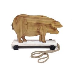 a wooden toy with wheels and a pig on it's back, sitting next to a rope