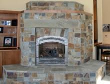 a living room with a stone fireplace and bookshelves