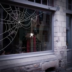 a spider web hanging from the side of a window in front of a brick building