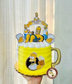 someone holding up a beer mug with the characters from the simpsons on it's side