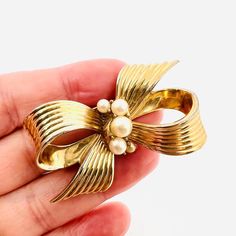 Gorgeous Vintage Signed JOMAZ Joseph Mazer Faux Pearl Gold Plated Bow Brooch. Heavily gold plated metal (looks like fine jewelry) with faux pearls in a bow design. Signed on reverse. In excellent vintage condition with minimal age appropriate wear. Measures 2 1/8 inches long by 1 3/8 inches wide. Clasp secure Gold Brooch With Decorative Bow As Gift, Gold Brooches With Decorative Bow For Gift, Elegant Gold-tone Brooches For Formal Occasions, Gold Bow Brooches For Formal Occasions, Gold Bow Brooch For Evening, Gold Bow Brooch For Evening Wear, Elegant Gold-tone Brooches For Gifts, Formal Gold Brooch With Bow, Vintage Gold Brooch With Bow