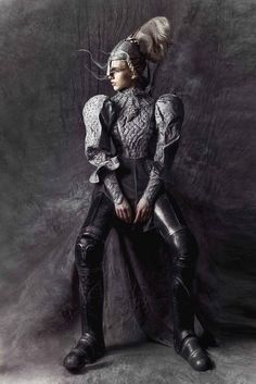 a woman sitting on top of a chair wearing armor