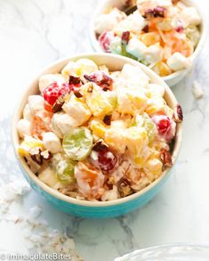 two bowls filled with fruit salad sitting on top of a marble countertop next to another bowl