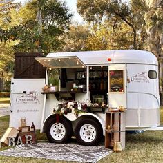 a food truck parked in the grass with its door open and decorations on it's side