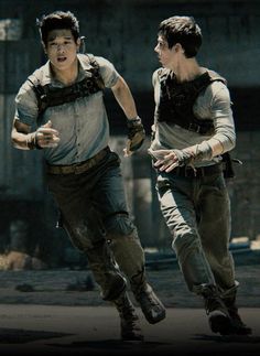 two young men running in the street with one holding his hand out to another man