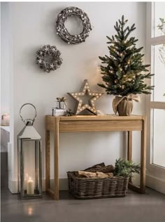 a small christmas tree sitting on top of a wooden table next to a basket filled with presents