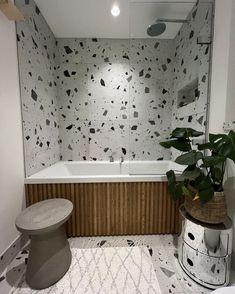 a bathroom with black and white wallpaper, a plant in the corner and a bathtub