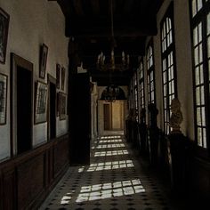 an empty hallway with lots of windows and pictures on the wall