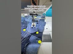 the sewing machine is working on some blue jeans with yellow balls in front of it