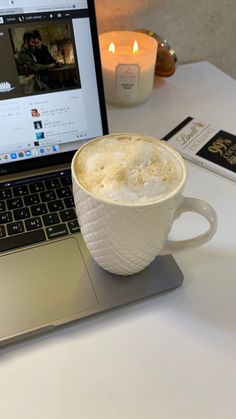 a laptop computer sitting on top of a white table next to a cup of coffee