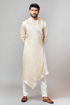 Champagne long kurta with asymmetric hem, button placket and placement embroidered sleeves. Paired with cream pajama-pants.
Component: 2
Embroidered
Neckline: Round
Sleeve Length: Long
Fabric: Kurta: Linen Satin; Pajama Pant: Malai Cotton
Color: Gold

Asymmetric hem
Overlap style
Button placket
Draped double panels - Aza Fashions Satin Kurta, Minimal Embroidery, Asymmetric Kurta, Satin Pajama Pants, Cotton Pajama Pants, Kurta Men, Indian Men Fashion, Cloth Design, Mens Clothing Store