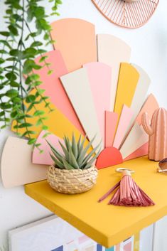 a yellow table topped with a potted plant next to a colorful fan wall clock