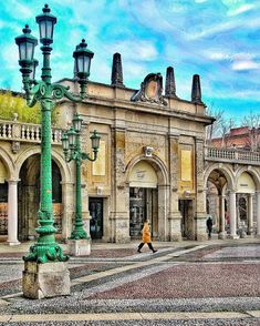 a person walking down the street in front of an old building with columns and arches