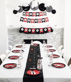 a long table set with black and red place settings for an event or birthday party