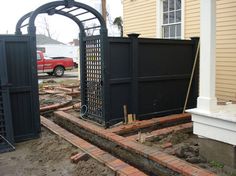 an outdoor area with a gate and some bricks in front of a house that is under construction