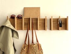 two purses are hanging on the wall next to some wooden pegs and hooks