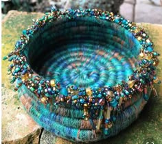 a blue basket with beads on it sitting on top of a rock