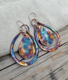 Copper Dangle Earrings Each earring is handmade from copper and hammered for texture. The vibrant colors are created using a flame painting technique. Each earring has a unique, one-of-a-kind look. The earrings are sealed to protect the colors. These colorful boho earrings swing from sterling silver ear wire and measure approximately 2 1/4 inches in total. Because each earring is handmade, the pair you receive may vary from the ones shown in the photos. The colors may be different- this will als Artistic Multicolor Copper Jewelry, Copper Teardrop Earrings With Patina, Multicolor Nickel-free Copper Earrings, Nickel-free Multicolor Copper Earrings, Handmade Multicolor Copper Earrings, Multicolor Copper Dangle Earrings, Flame Painting, Enameling Jewelry, Patina Jewelry