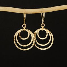 This unique pair of Three Gold Circles Earrings is handcrafted with great care from high-quality 14K Gold Filled. Lever-back ear wires make the earrings extremely convenient to wear. The earrings are hand-textured and polished to a beautiful shine.  MATERIALS AND SIZE ◆ Metal - 14K Gold Filled ◆ Earrings measure approx. 40 mm/ 1.57 inches from the top of the ear wire GIFT AND PACKAGING ◆ All jewelry is packed beautifully in a branded gift box. ◆ If the item is intended as a gift, please pick the Handmade 14k Gold Hoop Earrings, Circle Earrings With Ear Wire For Anniversary, Anniversary Jewelry With Matching Earrings, Circular Earrings With Ear Wire For Anniversary, 14k Gold Filled Round Earrings, Circular Anniversary Earrings With Ear Wire, Handmade 14k Gold Earrings For Everyday, Everyday Handmade 14k Gold Earrings, Modern Jewelry With Lever Back Ear Wires For Anniversary