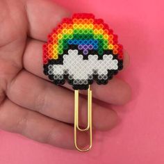 a hand holding a pin with a rainbow on it