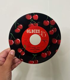 a hand holding up a record with cherries on the side and an oldie's label