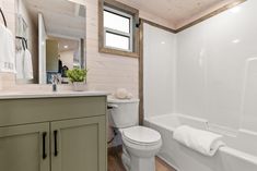 a white toilet sitting next to a bath tub in a bathroom under a wooden ceiling