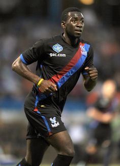 a male soccer player is running with the ball in his hand and looking at the camera