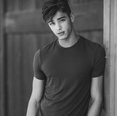 black and white photograph of a young man leaning against a wall