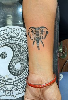 an elephant tattoo on the left wrist and right hand with yin sign in front of it