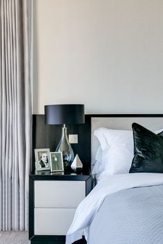 a bed with white sheets and black pillows