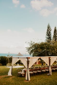 an outdoor wedding setup with white draping and tables set up on the grass