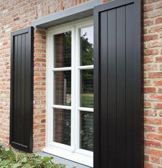 an open window with black shutters on a brick building