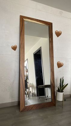 a mirror sitting on top of a wooden floor next to a potted plant