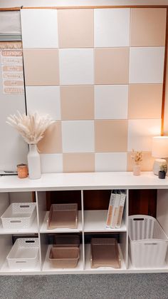 a white shelf with baskets and boxes on it in front of a checkered wall