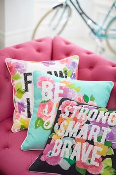 two colorful pillows sitting on top of a pink chair with the words be you tiful