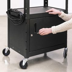 a person pushing a cart with a black box on it's wheels and holding the handle