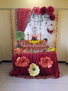 a table with flowers and candles on it in front of a wall hanging from the ceiling