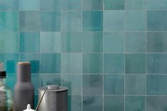 bottles and containers sit on a counter in front of a blue tiled wall