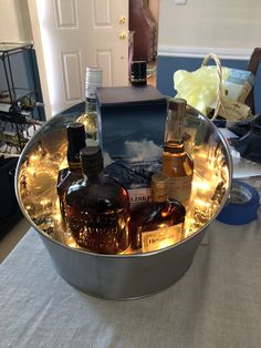 two bottles of whiskey are in a metal bowl on a table with other liquors