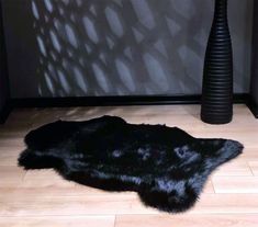 a black sheepskin rug on the floor next to a vase