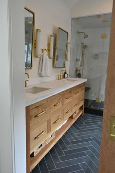 a bathroom with two sinks and mirrors on the wall next to a walk in shower