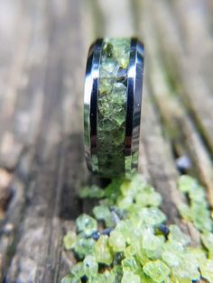 a wedding ring with green moss growing out of it on top of a wooden table