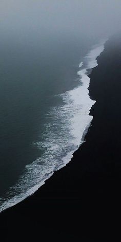 an airplane is flying over the ocean on a foggy day with black and white waves